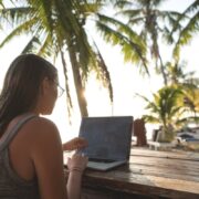 Digital nomad working on laptop under palm trees